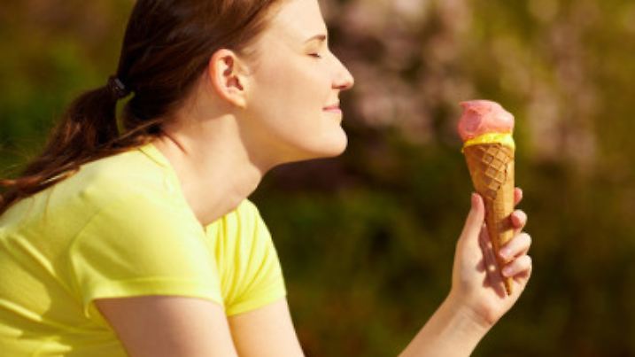 Lachende Frau isst Eiscreme in der Waffel im Sommer