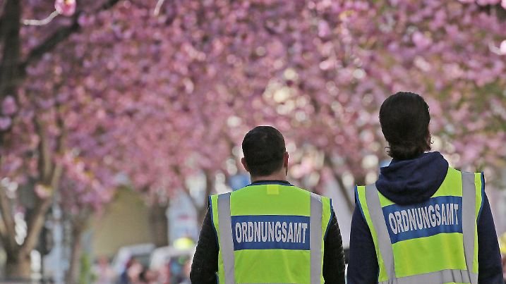 06.04.2020, Nordrhein-Westfalen, Bonn: Mitarbeiter des Ordnungsamtes patrouillieren in der Bonner Nordstadt unter den Kirschblüten. Bei schönem Wetter zieht die Blüte zahlreiche Schaulustige an. Zur Eindämmung des Coronavirus hat NRW alle Ansammlungen ab drei Personen in der Öffentlichkeit verboten. Foto: Oliver Berg/dpa +++ dpa-Bildfunk +++