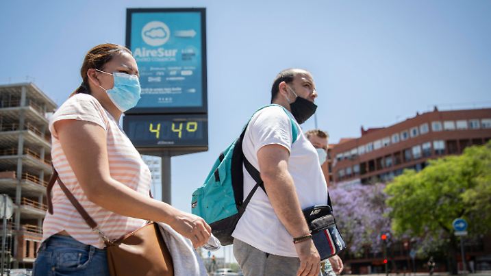 22.05.2020, Spanien, Sevilla: Mehrere Personen gehen in Sevilla an einer Tafel vorbei, die eine Temperatur von 44 Grad anzeigt. Eine Hitzewelle trifft derzeit mehrere Gebiete Spaniens. Foto: María José López/EUROPA PRESS/dpa +++ dpa-Bildfunk +++