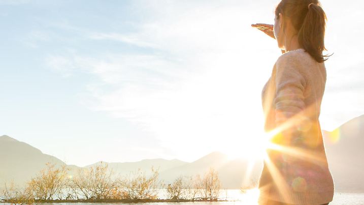 Young cheerful woman by the lake watching the sunset.