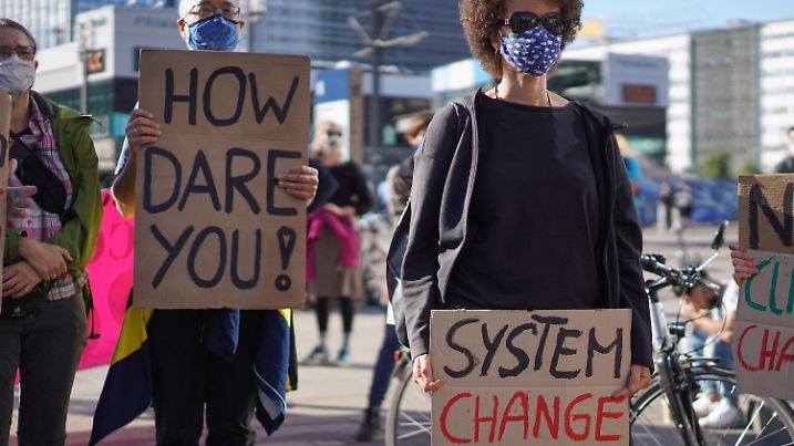 06.07.2020, Berlin: Teilnehmer mit Mundschutz zeigen Pappkartons mit den Aufschriften "How dare you!" und "System change" auf der Klima-Demonstration "Berlin4Future" auf dem Alexanderplatz. Aus Protest gegen das Gesetzespaket zum Kohleausstieg will die Initiative ·Berlin4Future· künftig an jedem ersten Montag im Monat auf dem Alexanderplatz demonstrieren. Neben den Schulstreiks fürs Klima solle es auch eine Plattform für berufstätige Erwachsene geben, die mit der aktuellen Politik und dem Konjunkturpaket im Sinne der Klimagerechtigkeit nicht einverstanden sind. Foto: Jörg Carstensen/dpa +++ dpa-Bildfunk +++