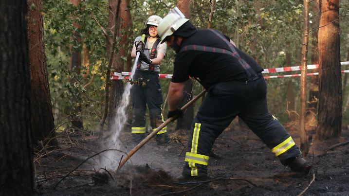 06.08.2020, Nordrhein-Westfalen, Dormagen: Feurwehrleute bekämpfen im Naturschutzgebiet "Zonser Heide" mit Wasser und Mistgabel einen Waldboden-Brand. Eine größere Fläche Wald und Wiesen stand am Morgen in Flammen, verletzt wurde laut Polizei niemand. Foto: David Young/dpa +++ dpa-Bildfunk +++