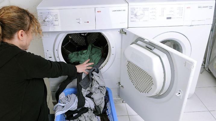 ARCHIV - ILLUSTRATION - Eine Hausfrau befüllt am 24.03.2009 in Straubing (Bayern) einen Wäschetrockner mit frisch gewaschener Kleidung. Foto: Armin Weigel/dpa (zu dpa 'Frauen arbeiten etwas mehr als Männer - aber viel häufiger unbezahlt' vom 18.05.2015) +++(c) dpa - Bildfunk+++