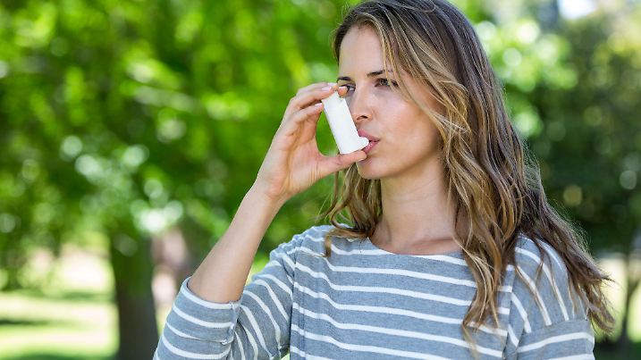 Woman using asthma inhaler in a park