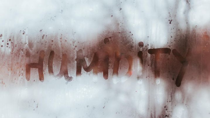 Humidity word written on wet window with condensate. High level of dampness in apartment.