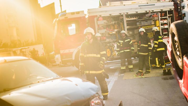 Front view of a group of firefighters at a car accident scene, fire engine in background.