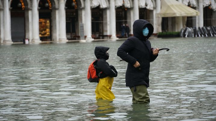08.12.2020, Italien, Venedig: Passanten bahnen sich ihren Weg durch den überfluteten Markusplatz. Starke Regenfälle und steigende Pegel haben im italienischen Venedig Teile der Stadt überflutet. Foto: Lapresse/Anteo Marinoni/LaPresse via ZUMA Press/dpa +++ dpa-Bildfunk +++