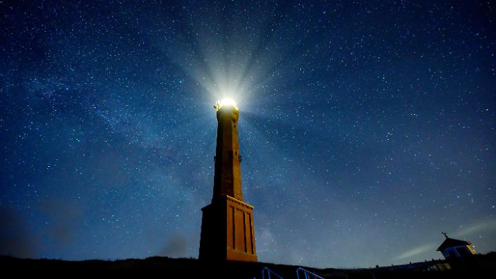 28.02.2020, Niedersachsen, Norderney: Bei klarem Himmel sind die Sterne über Norderney zu sehen, während das Licht des Leuchtturms der Insel hell strahlt. Foto: Mohssen Assanimoghaddam/dpa +++ dpa-Bildfunk +++