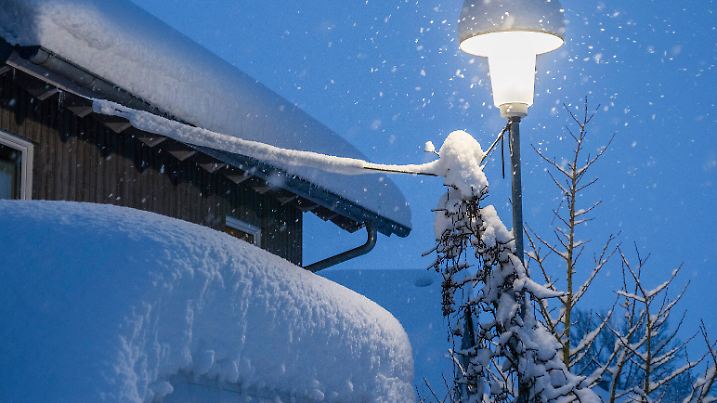 Eine Strassenlaterne leuchtet an einem Wintermorgen bei Schneefall zur blauen Stunde. Leutkirch, Baden Württemberg, Deutschland Winter im Allgäu *** A streetlight shines on a winter morning during snowfall at blue hour Leutkirch, Baden Württemberg, Germany Winter in Allgäu