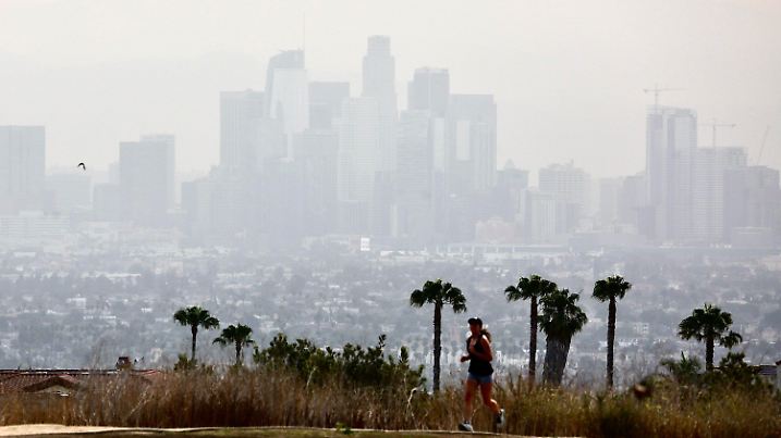 17.06.2021, USA, Los Angeles: Eine Freizeitsportlerin läuft in der Hitze in der Kenneth Hahn State Recreation Area, mit der Skyline von Los Angeles im Hintergrund. Der Westen der USA brütet unter einer anhaltenden Hitzewelle bei Temperaturen bis 45 Grad Celsius. Foto: -/XinHua/dpa +++ dpa-Bildfunk +++
