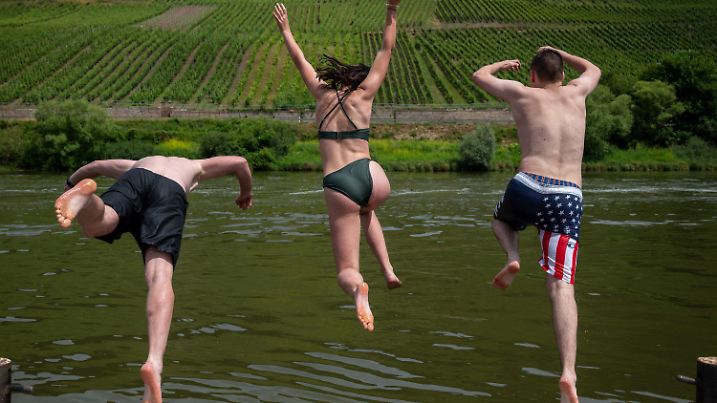 26.06.2021, Rheinland-Pfalz, Traben-Trarbach: Jonah (l-r), Lena und Moritz springen zur Abkühlung bei Traben-Trarbach in die Mosel. Am Wochenende sollen die Temperaturen in Rheinland-Pfalz um die 30 Grad erreichen. Foto: Harald Tittel/dpa +++ dpa-Bildfunk +++