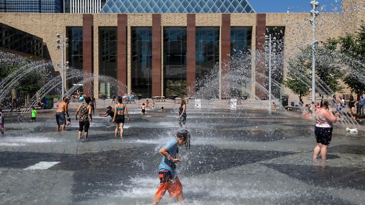 30.06.2021, Kanada, Edmonton: Menschen kühlen sich in einem Pool des Rathauses ab. Die anhaltende Hitzewelle im Westen Kanadas hat für neue Höchsttemperaturen gesorgt und zu mehreren Todesfällen beigetragen. Foto: Jason Franson/The Canadian Press/AP/dpa +++ dpa-Bildfunk +++