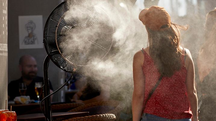 29.06.2021, Spanien, Madrid: Eine Frau kühlt sich vor der Hitze mit einem Wasserdampfdiffusor vor einem Restaurant in der Alcala Straße. Es werden Höchsttemperaturen von bis zu 36 Grad Celsius erwartet. Foto: Jesús Hellín/EUROPA PRESS/dpa +++ dpa-Bildfunk +++
