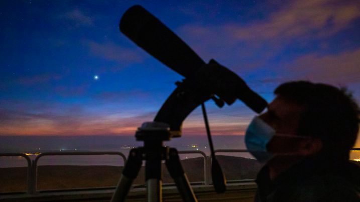 Man watches a conjunction  between Jupiter and Saturn  seen above Split, after sunset , in Split, Croatia,on December 21, 2020. This event, known as a great conjunction, happens about once every 20 years.But the closeness of the two planets makes thi