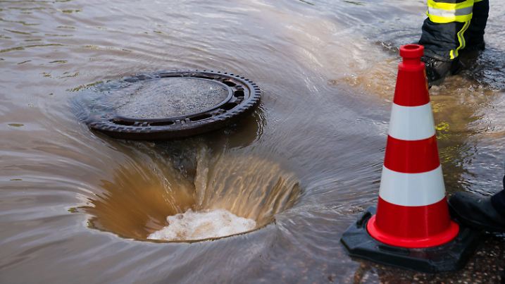 dpatopbilder - 09.07.2021, Bayern, Ansbach: Wasser fließt durch eine offene Kanalisationsluke. Insbesondere im Süden Deutschlands ist es am Freitag zu zahlreichen wetterbedingten Notfällen und Einsätzen von Polizei und Feuerwehr gekommen. Foto: Nicolas Armer/dpa +++ dpa-Bildfunk +++