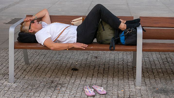 14.08.2021, Spanien, Madrid: Eine Frau liegt bei hohen Temperaturen auf einer Bank. In Spanien brachte die bisher schlimmste Hitzewelle des Sommers Millionen Menschen ins Schwitzen. Die Werte kletterten in vielen Gebieten des Landes deutlich über die 40-Grad-Marke, auch in der Hauptstadt Madrid. Foto: Andrea Comas/AP/dpa +++ dpa-Bildfunk +++