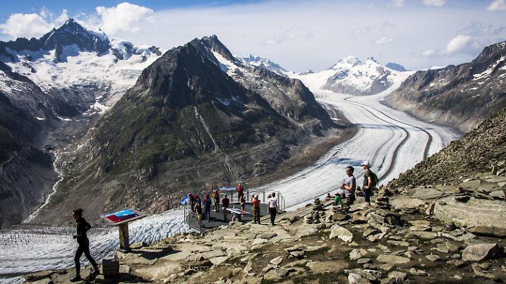 16.08.2021, Schweiz, Fiesch: Menschen beobachten den Aletschgletscher vom Aussichtspunkt Eggishorn oberhalb von Fiesch. Der Aletschgletscher ist der größte Gletscher der Alpen und befindet sich im südlichen Teil der Schweiz im Kanton Wallis. Foto: Jean-Christophe Bott/KEYSTONE/dpa +++ dpa-Bildfunk +++
