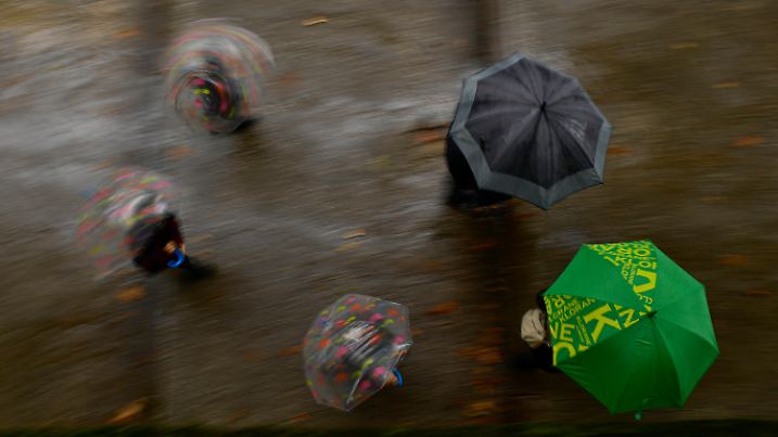 03.10.2020, Spanien, Pamplona: Fußgänger halten Abstand, während sie sich an einem Herbsttag unter Regenschirmen vor dem Regen schützen. Foto: Alvaro Barrientos/AP/dpa +++ dpa-Bildfunk +++
