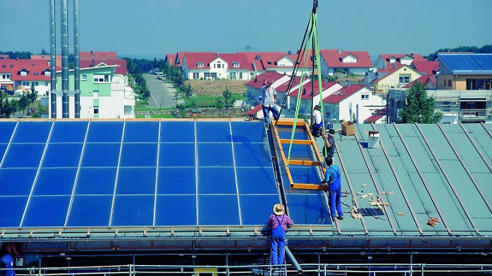 Handwerker bringen Solarzellen auf einem Hausdach an.