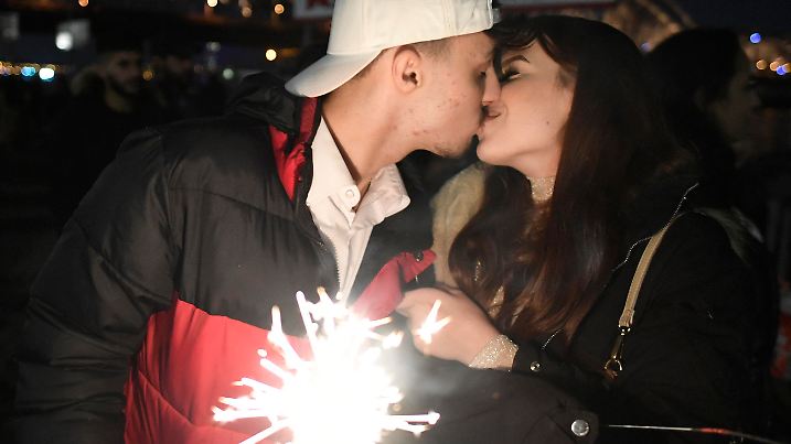 31.12.2021, Nordrhein-Westfalen, Köln: Zum Jahreswechsel küsst sich dieses junge Liebespaar im Schein einer Wunderkerze. In der Silvesternacht ist rund um den Dom und der Altstadt eine Böllerverbotszone eingerichtet. Foto: Roberto Pfeil/dpa +++ dpa-Bildfunk +++