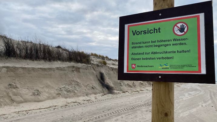16.01.2022, Niedersachsen, Norderney: An einer Dünenabbruchkante auf der Insel Norderney warnt ein Schild des Niedersächsischen Landesbetriebs für Wasserwirtschaft, Küsten- und Naturschutz (NLWKN) Spaziergänger vor dem Betreten eines Strandabschnittes bei Hochwasser. In dem Bereich war Anfang Januar eine Frau bei stürmischem Wetter beim Abbruch einer Dünenkante teils verschüttet worden. Die Schilder wurden nun zur Warnung aufgestellt. (zu dpa: "Sturm an der Nordseeküste erwartet - Schilder warnen vor Dünenabbruch") Foto: Volker Bartels/dpa +++ dpa-Bildfunk +++