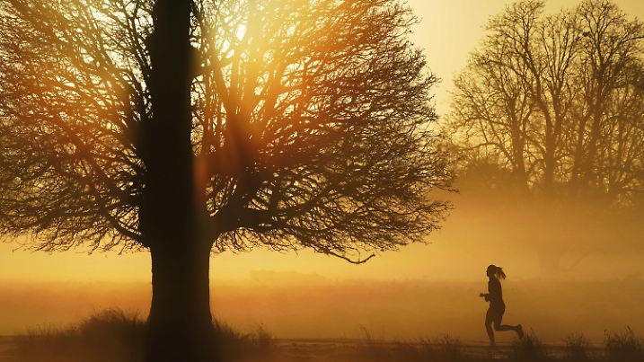 17.01.2022, Großbritannien, London: Eine Frau joggt auf einem Weg, während am Horizont die Sonne aufgeht. Foto: Jonathan Brady/PA Wire/dpa +++ dpa-Bildfunk +++