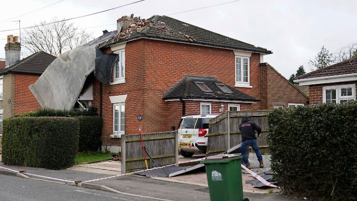 A man cleans up a driveway after a flat roof from a nearby block of flats was blown off and landed on a house in Bitterne, Southampton, England, Saturday Feb. 19, 2022. Crews cleared fallen trees and worked to restore power to about 400,000 people in Britain as Western Europe cleaned up Saturday after one of the most damaging storms for years. At least nine people were killed, many by falling trees, in Ireland, Britain, Belgium and the Netherlands. Named Storm Eunice by the British and Irish weather services, and Zeynep in Germany, Friday's storm was the second to hit the region in a week. (Andrew Matthews/PA via AP)