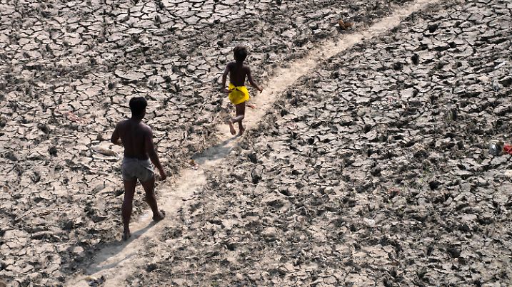 A man and a boy walk across an almost dried up bed of river Yamuna following hot weather in New Delhi, India, Monday, May 2, 2022. An unusually early and brutal heat wave is scorching parts of India, where acute power shortages are affecting millions as demand for electricity surges to record levels. (AP Photo/Manish Swarup)