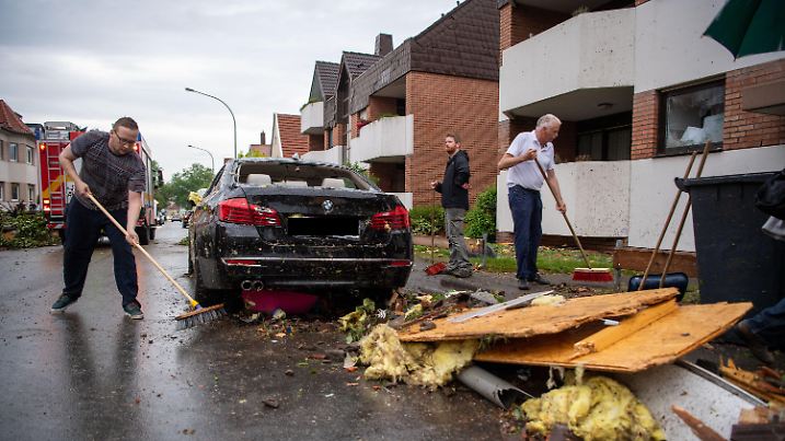 20.05.2022, Nordrhein-Westfalen, Paderborn: Leute fegen Trümmer von der Straße. Ein Unwetter hat auch in Paderborn große Schäden angerichtet. Foto: Lino Mirgeler/dpa +++ dpa-Bildfunk +++