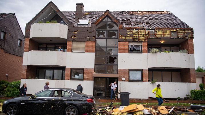 20.05.2022, Nordrhein-Westfalen, Paderborn: Eine Frau schaufelt Ziegel vom abgedecken Dach eines Hauses in eine Mülltonne. Ein Unwetter hat auch in Paderborn große Schäden angerichtet. Foto: Lino Mirgeler/dpa +++ dpa-Bildfunk +++