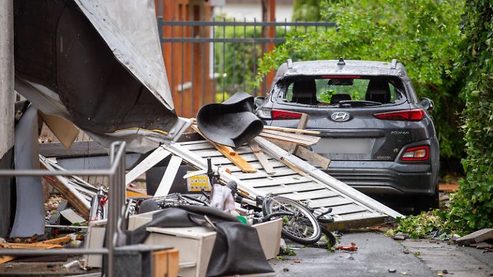 20.05.2022, Nordrhein-Westfalen, Paderborn: Ein beschädigtes Auto steht in den Trümmern eines abgedeckten Hauses. Ein Unwetter hat auch in Paderborn große Schäden angerichtet. Foto: Lino Mirgeler/dpa - ACHTUNG: Autokennzeichen gepixelt +++ dpa-Bildfunk +++