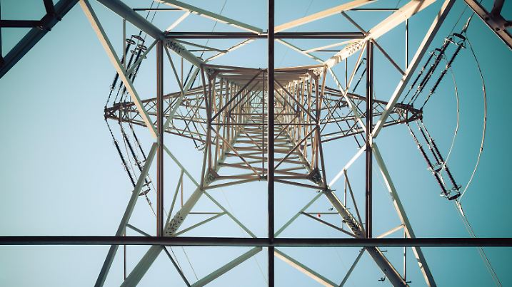 Picture of an electrical tower or pylon, blue sky in the background. Power grid or smart grid.