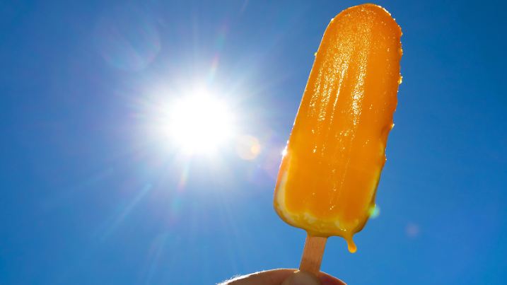 DEU/Deutschland/Brandenburg, ILLUSTRATION, 06.08.2018, Hitzewelle in Deutschland, Symbolfoto. Ein in der Waerme schmelzendes Eis (Eis am Stiel) ist vor der strahlenden Sonne und dem wolkenlosen blauen Himmel zu sehen.