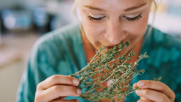 Woman smells fresh herbs, part of a 10 photo series, creative color editing with added grain