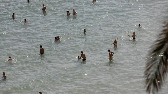 23.07.2022, Spanien, Cala Major: Menschen halten sich am Strand von Cala Major, in der Nähe von Palma auf Mallorca, im Wassr auf. Auf der spanischen Urlaubsinsel sind in diesen Tagen nicht nur der Sand und die Luft sehr heiß, sondern auch das Meereswasser erreicht ungewöhnlich hohe Temperaturen. (zu dpa Hitze auf Mallorca - Meer vor dem «Ballermann» wird zur warmen Brühe) Foto: Clara Margais/dpa +++ dpa-Bildfunk +++