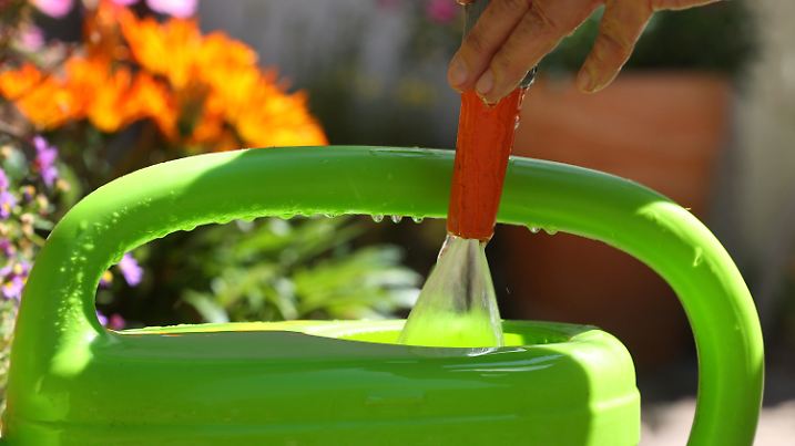 18.07.2022, Bayern, Kaufbeuren: Eine Frau befüllt in einem Garten eine Gießkanne mit Wasser aus einem Gartenschlauch. Foto: Karl-Josef Hildenbrand/dpa +++ dpa-Bildfunk +++