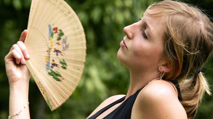 Gegen die schwüle Luft wedelt sich Maike am Dienstag (22.05.2007) im Stadtpark in Moers mit einem Fächer eine frische Brise zu. Bei Temperaturen um 25 Grad und bedecktem Himmel ist es außergewöhnlich schwül, Gewitter sollen am Abend nicht nur in Nordrhein-Westfalen für Abkühlung sorgen. Foto: Roland Weihrauch dpa/lnw +++(c) dpa - Bildfunk+++