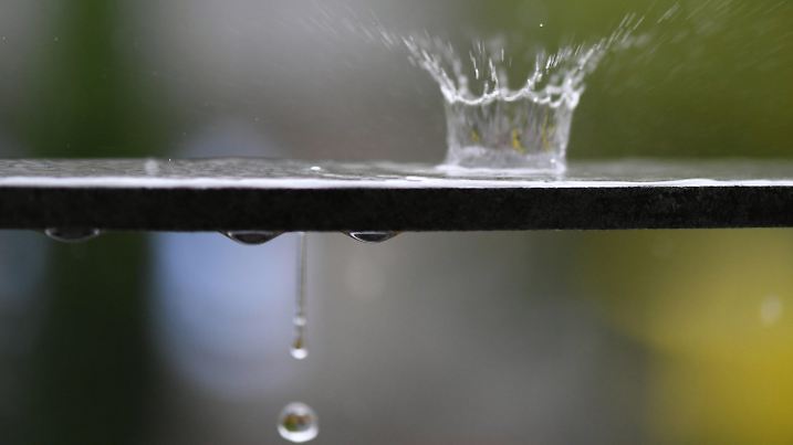 28.07.2019, Baden-Württemberg, Freiburg: Wasser spritzt bei einem Regenschauer von der Wasseroberfläche auf einem Geländer in die Höhe. Foto: Patrick Seeger/dpa +++ dpa-Bildfunk +++