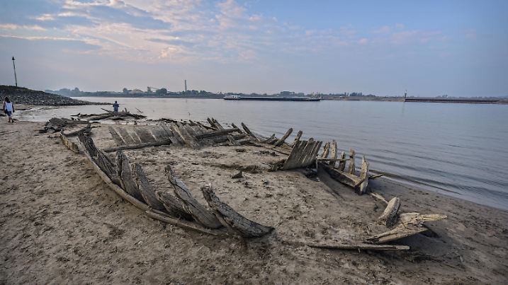 Niedrigwasser / Trockenheit am Rhein bei Salmorth / Kleve, nahe Emmerich. Ein altes Schiffswrack wird durch den extrem niedrigen Wasserstand freigelegt. Extremes Niedrigwasser am Rhein bei Salmorth / Kleve, nahe Emmerich. Pegel bei Emmerich fällt unter Nullmarke. Das Foto zeigt den Stand am Vorabend des 18. August. Bereits am Dienstag war der Wasserstand des Rheins teils historisch niedrig nun ist er in Emmerich weiter gefallen. Die Trockenheit machen die Folgen des Klimawandels von Jahr zu Jahr staerker sichtbar. Der niedrige Wasserstand des Rheins hat das 123 Jahre altes Wrack eines Frachtschiffs an der Grenze zu den Niederlanden wie noch nie freigelegt. Von ueberall kommen Menschen um das Naturereignis mit eigenen Augen zu sehen.