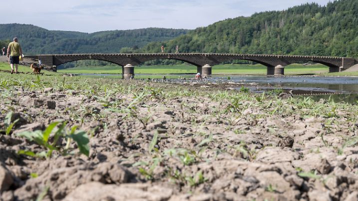 17.08.2022, Hessen, Vöhl: Spaziergänger laufen über die alte Aseler Brücke im Edersee, die durch den niedrigen Wasserstand nach anhaltender Trockenheit frei liegt. Bei einem regulären Füllstand des Sees liegt die Brücke metertief unter der Wasseroberfläche. Als Teil des ·Edersee-Atlantis· ist sie zum touristischen Anziehungspunkt geworden. Foto: Boris Roessler/dpa +++ dpa-Bildfunk +++