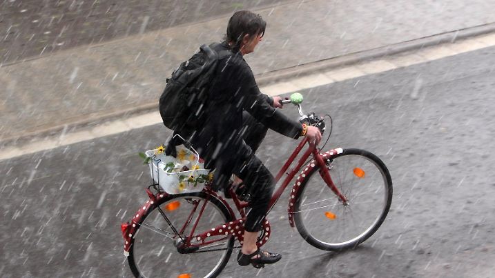 Gewitter mit Starkregen in Hofheim, Main Taunus Kreis, Hessen, Deutschland. Durchnässte Frau fährt mit ihrem Fahrrad auf einer Straße. *** Thunderstorm with heavy rain in Hofheim, Main Taunus Kreis, Hesse, Germany Soaked woman riding her bicycle on a road