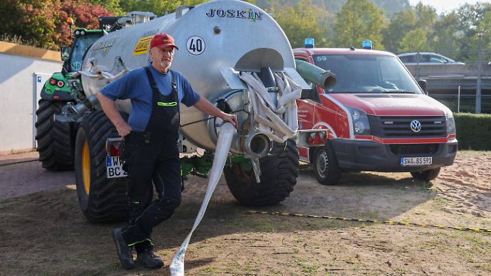 12.09.2022, Hessen, Bad Schwalbach: Benno Burggraf steht an seiner Zugmaschine mit Wassertank und bekommt mit einer Pumpe der Feuerwehr Wasser aus dem Becken, um anschließend die Bäume im Kurpark zu bewässern. Das Schwimmbad in Bad Schwalbach lädt alle dazu ein, sich nach dem Ende der Saison gebrauchtes Wasser zum Gießen abzuholen. Es gibt etwa 800 000 Liter Wasser zu verschenken. Das Bad hatte am 4. September geschlossen, danach dauerte es acht Tage bis das Chlor zerfällt. Foto: Jörg Halisch/dpa +++ dpa-Bildfunk +++