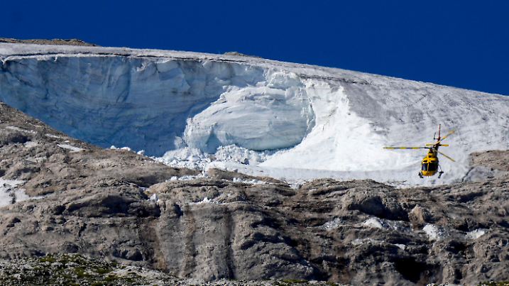 06.07.2022, Italien, Canazei: Ein Rettungshubschrauber fliegt über den Punta-Rocca-Gletscher in den italienischen Alpen. Nach dem massiven Gletscherbruch und einer Lawine geht in den Dolomiten die Suche nach weiteren Toten unter erschwerten Bedingungen weiter. (Illustration zu "Deutsche nach Dolomiten-Unglück aus Klinik entlassen") Foto: Luca Bruno/AP/dpa +++ dpa-Bildfunk +++
