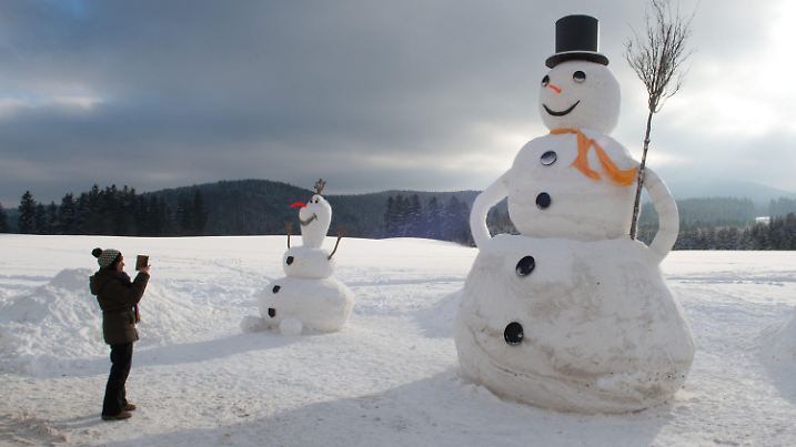 ARCHIV - Eine Frau fotografiert am 10.01.2017 in Eibenstock (Sachsen) einen 6,50 Meter großen Schneemann. Die Nase des Schnee-Riesen besteht aus einem lackieren Rettich. Der kleinere Schneemann misst drei Meter. (zu dpa "Weiß und kugelrund - Wissenswertes und Kurioses zum Schneemann" vom 16.12.2017) Foto: Sebastian Kahnert/dpa-Zentralbild/dpa +++(c) dpa - Bildfunk+++