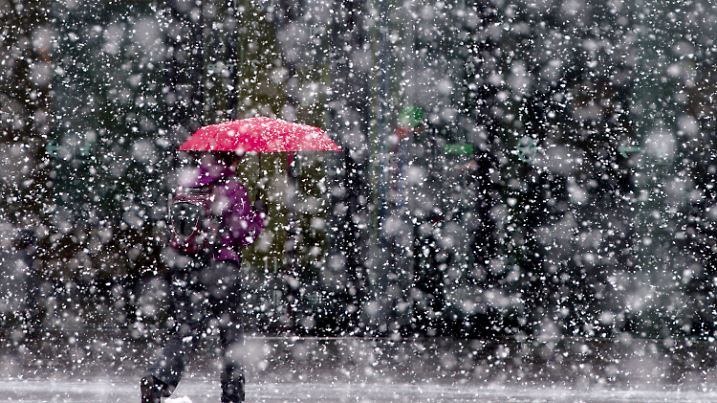 ARCHIV - Eine Frau geht bei starkem Schneefall am 24.01.2014 in Stuttgart (Baden-Württemberg) mit einem roten Schirm über das Messegelände. Meteorologen kündigten flächendeckend Schnee im Südwesten an. Die ersten Schneeschauer ziehen im Südosten von Baden-Württemberg schon am zweiten Weihnachtsfeiertag ein. Foto: Sebastian Kahnert/dpa (zu lsw «Guten Rutsch - Mit Schnee und Glatteis ins neue Jahr» vom 25.12.2014) +++(c) dpa - Bildfunk+++
