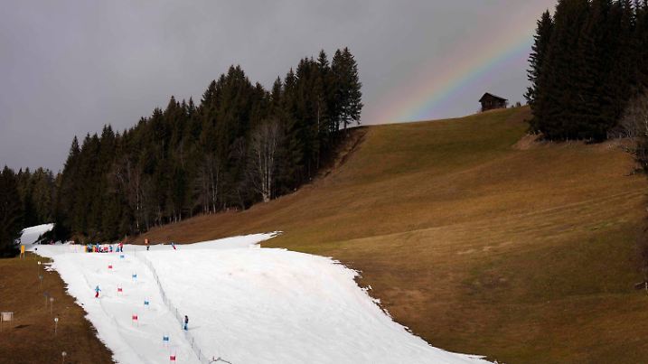 05.01.2023, Österreich, Filzmoos: Skifahrer fahren eine Piste neben einer Wiese, auf der kein Schnee liegt, herab. Der spärliche Schneefall und das für die Jahreszeit untypisch warme Wetter in weiten Teilen Europas haben dazu geführt, dass viele Berggipfel, auf denen normalerweise Schnee liegt, mit grünem Gras bedeckt sind. Das bereitet den Betreibern von Skipisten und den Liebhabern des alpinen Weiß zu dieser Jahreszeit Kopfzerbrechen. Foto: Matthias Schrader/AP/dpa +++ dpa-Bildfunk +++
