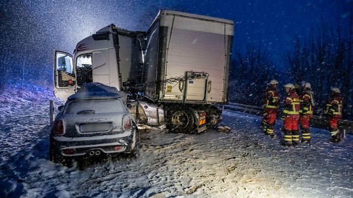 19.01.2023, Nordrhein-Westfalen, Kierspe: Einsatzkräfte stehen an einer Steigung, an der ein Sattelschlepper in ein Auto gerutscht ist. Einige Zentimeter Schnee bis ins rheinische Flachland haben Pendlern am Donnerstagmorgen viel Geduld abverlangt. Obwohl der Winterdienst im Großeinsatz war, gab es in weiten Teilen von Nordrhein-Westfalen Behinderungen auf den Straßen. (zu dpa «Schnee behindert Verkehr in NRW - Busse in Wuppertal fahren nicht») Foto: Markus Klümper/dpa - ACHTUNG: Kfz Kennzeichen wurde aus rechtlichen Gründen gepixelt +++ dpa-Bildfunk +++