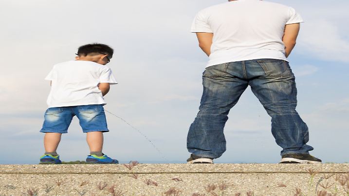 father and son standing on a stone platform and pee together with natural background