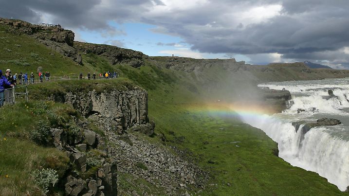 Touristen laufen auf einem Weg über dem Wasserfall Gullfoss (Goldfall) an der Straße F 35 nahe dem Geothermalgebiet Haukadalur in Island, aufgenommen am 12.07.2006. Der Fluss Hvita stürzt an dieser Stelle in zwei Stufen von jeweils über 30 Metern in eine Schlucht. Island ist eines der am dünnsten besiedelten Länder der Erde, auf 103.110 Quadratkilometern leben gerade 286.000 Einwohner, das sind 2,8 Einwohner je Quadratkilometer. Zwölf Prozent des Landes sind von Gletschern bedeckt, etwa elf Prozent von Lava. Island liegt genau auf der Bruchstelle der auseinander driftenden amerikanischen und eurasischen Kontinentalplatten. Die Insel gehört somit zu den vulkanisch aktivsten Gebieten der Erde. Die landschaftliche Vielfalt  und die einmaligen Kontraste machen Island für seine Besucher interessant. Jedes Jahr kommen mehr Urlauber auf die Insel im Nordatlantik und viele von ihnen verfallen der Schönheit des Naturparadieses. Dank der nördlichen Lage ist es von Mai bis Juli rund um die Uhr hell. Foto: Patrick Pleul   +++(c) dpa - Report+++