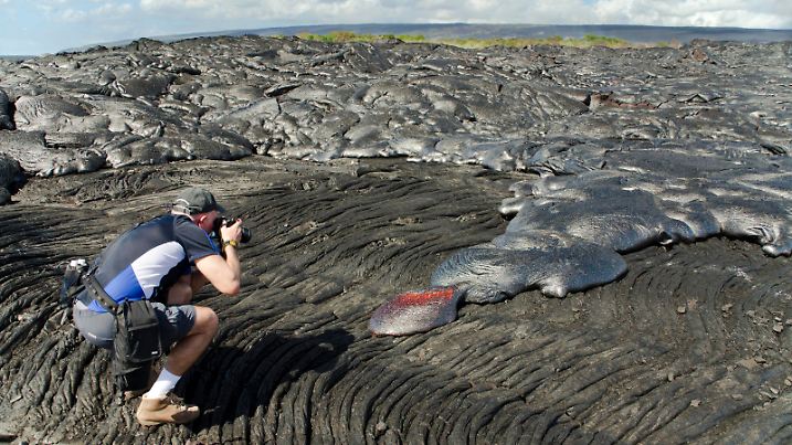 Hawaii, Big Island, Kalapana, Man photographs Pahoehoe lava flowing from Kilauea covering an older Pahoehoe flow. || Modellfreigabe vorhanden